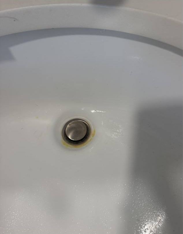 Bathroom sink before cleaning, with stains around the drain